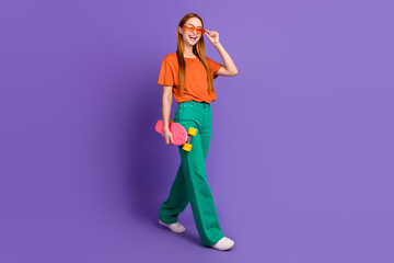 Full length photo of cheerful lovely girl walking summer day vacation time weekend isolated on purple color background