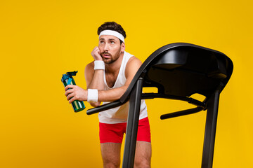 Portrait of exhausted minded person exercise treadmill hold bottle water look empty space isolated...