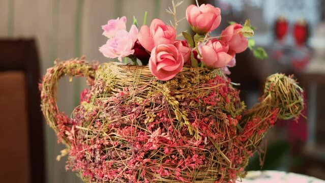Wickered watering-pot adorned by bush roses rotates close