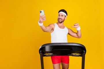 Photo of cool funky guy activewear walking treadmill showing thumb himself tacking selfie empty...