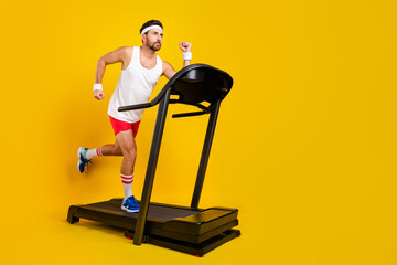 Full length profile portrait of focused strong young man run treadmill empty space isolated on yellow color background - obrazy, fototapety, plakaty