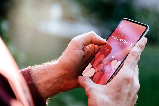 Man showing a digital Valentine's Day greeting card in the mobile phone screen.