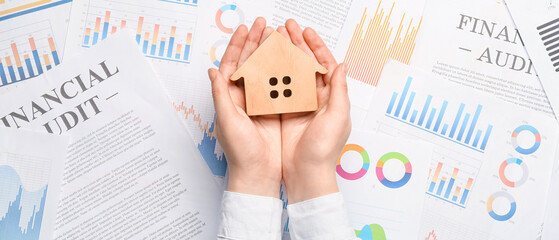 Obraz premium Real estate agent with wooden house on paper sheets