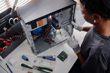 African american repair technician tightening cogs with screwdriver while repairing system unit in...