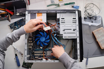Hands of unrecognizable male repairman arranging wires in disassembled system unit of computer - obrazy, fototapety, plakaty