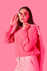 Young woman in stylish suit on pink background