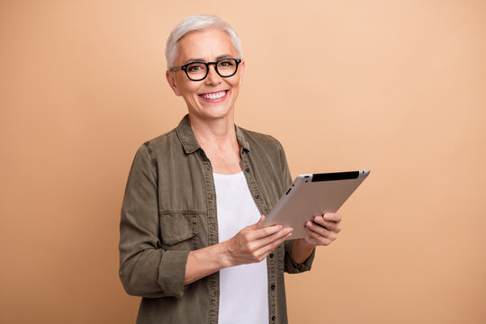 Photo of cheerful hr manager woman senior specialist white short hair using ipad for organization isolated on beige color background - Powered by Adobe