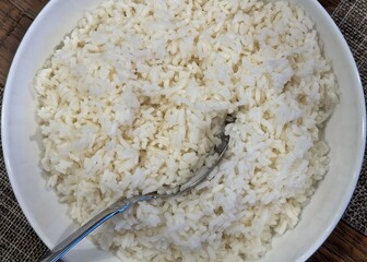 Large white bowl full of rice with a serving spoon