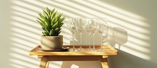 A beautifully designed wooden trolley with stemmed glasses and a potted plant.