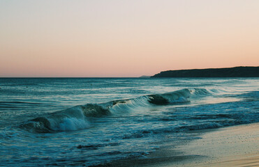 waves crashing on beach at sunset
