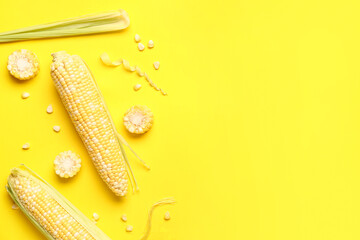 Obraz premium Fresh corn cobs and seeds on yellow background