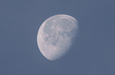 Waxing moon during daylight with blue sky background