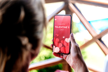 Woman showing a digital Valentine's Day greeting card in the mobile phone screen.