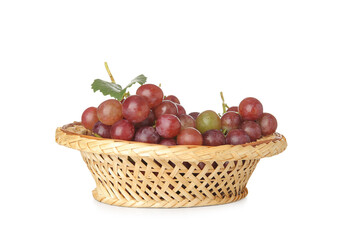Wicker bowl with tasty ripe grapes on white background