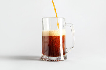 Pouring of tasty kvass into mug on grey background