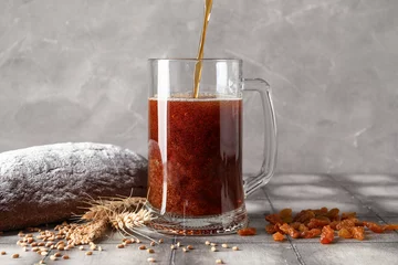 Fotobehang Pouring of tasty kvass into mug on table © Pixel-Shot