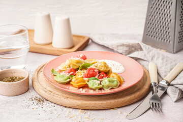 Plate of boiled colorful dumplings with cheese, basil and sour cream on white background