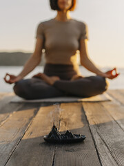 Girl practicing yoga and meditating on the beach at sunset.