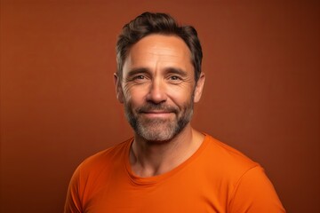 Handsome middle aged man in orange t-shirt on brown background