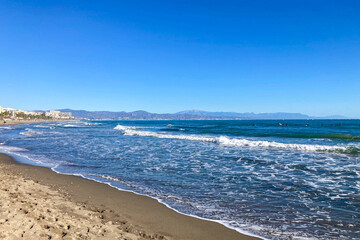Fuente Salud Beach, surfers training on waves in Benalmadena, Malaga, Spain