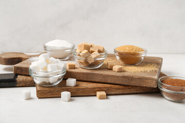 Bowls with different types of sugar on white background