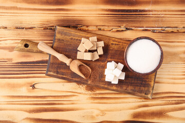 Board with different types of sugar on wooden background