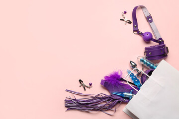 Shopping bag with different sex toys on pink background