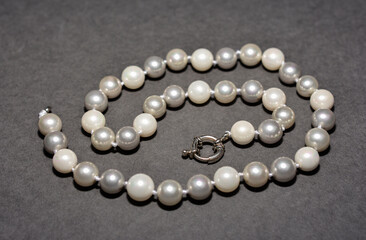 Pearl white round beads on a gray background. Women's elegant jewelry.