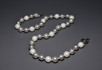 Pearl white round beads on a gray background. Women's elegant jewelry.