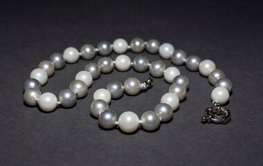 Pearl white round beads on a gray background. Women's elegant jewelry.