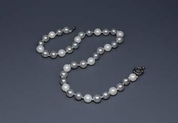 Pearl white round beads on a gray background. Women's elegant jewelry.