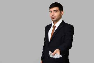 Young businessman with bribe on light background