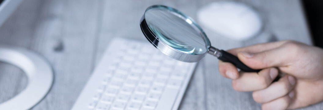 man hand magnifier on keyboard