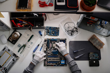 Technician working on installation of CPU into disassembled computer sitting at his desk in workshop