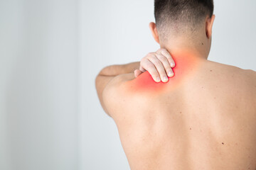 Rear view of a shirtless young man holding his neck in pain isolated on white background, man giving himself a massage on his neck, stress, neck pain, pain area highlighted in red
