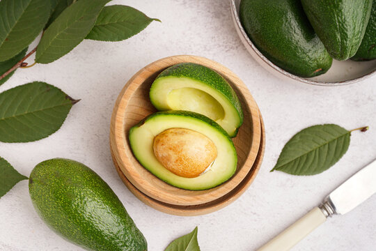 Bowls with fresh ripe avocados on white background