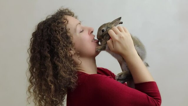 Woman holds and kisses dwarf rabbit, at white background