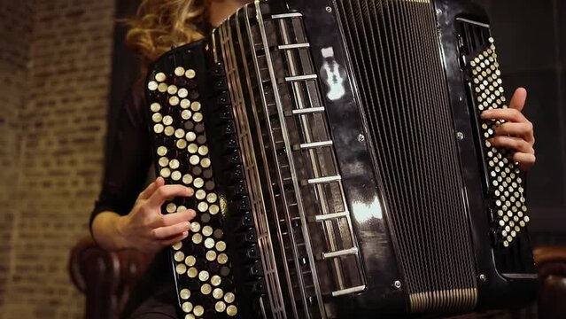 Fingers of woman push buttons on accordion during play
