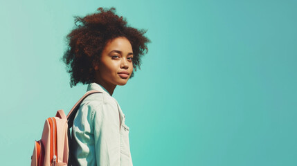 Schoolgirl Afro-American nationality with pink bag looking at camera against blue background. Back to school concept.