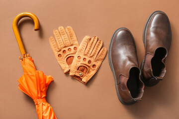 Stylish male gloves, shoes and umbrella on color background