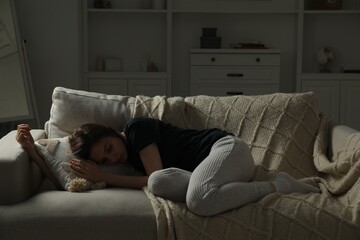 Sad young woman lying on sofa at home