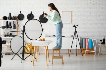 Female food photographer taking picture of cakes in studio