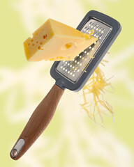 Grating cheese with hand grater on yellowish green background