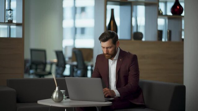 Serious manager making videocall at modern workplace. Man waving hand ending cal