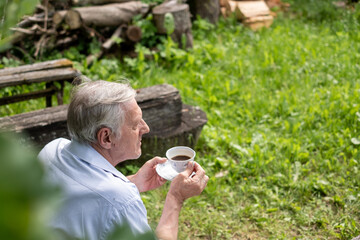 Elderly man with gray hair sipping coffee, with a focus on relaxation and the simplicity of...