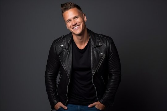 Portrait of a handsome young man in black leather jacket smiling at the camera.