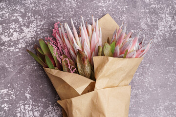 Bouquet with beautiful pink protea flowers in paper on grunge background
