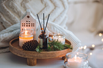Natural Christmas essential oil, home aroma diffuser. Burning candles, branches of fir tree. Cinnamon, vanilla smell. Aromatherapy, cozy atmosphere, holiday festive mood. Close up macro, wooden table