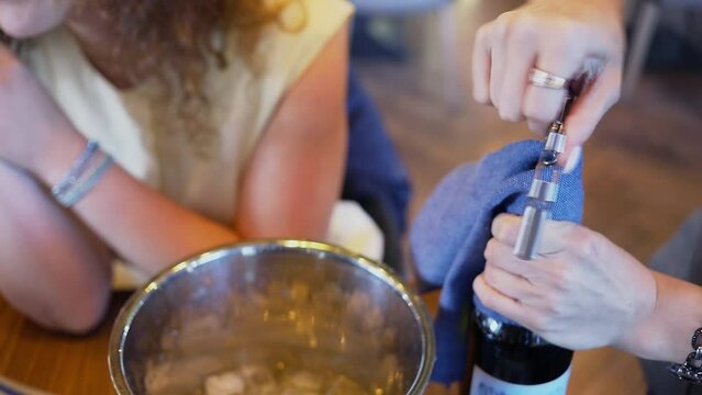 Woman uses corkscrew and opens bottle of wine. Slow motion