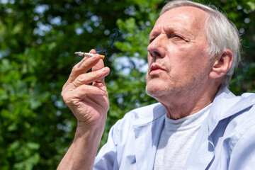 The senior enjoys a cigarette in the open air, a thought-provoking image on the themes of loneliness and parenting habits. Concept of unhealthy lifestyle, addictions and habits